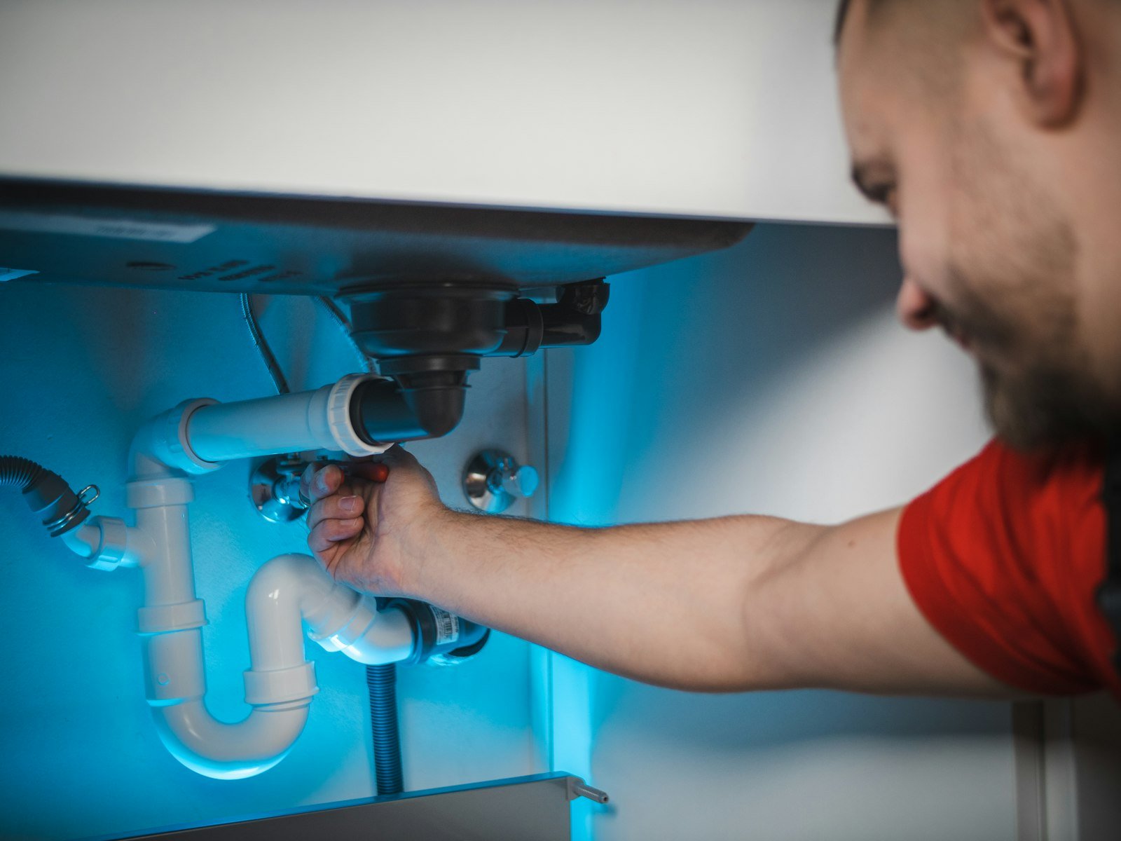 Plumber fixing the pipes under a sink